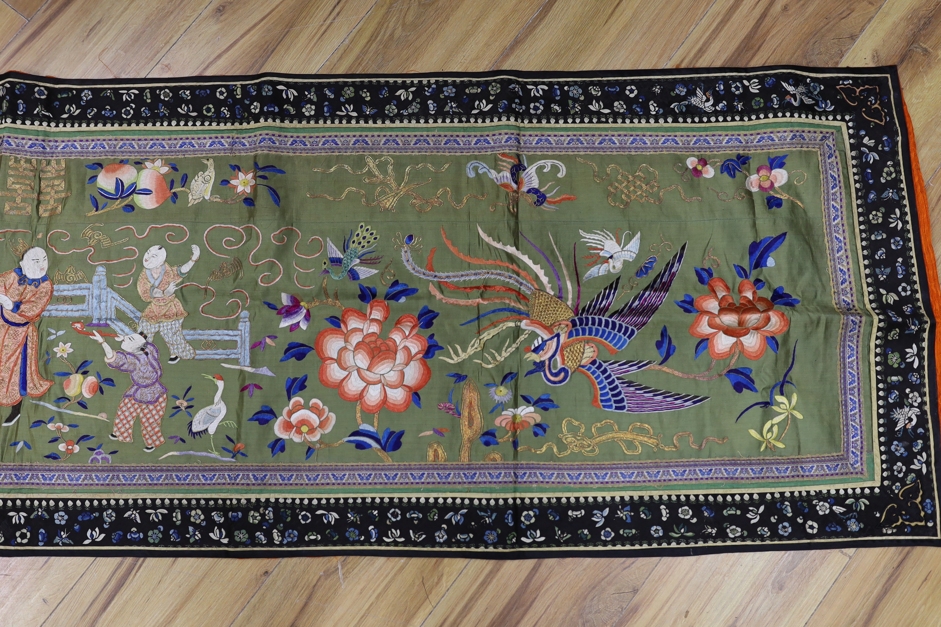 A long Chinese silk embroidered runner embroidered with the figure of Fu and boys, symbolic peaches, phoenix and flowers, possibly an altar cloth together with two other smaller runners, largest runner 202cm long x 55cm